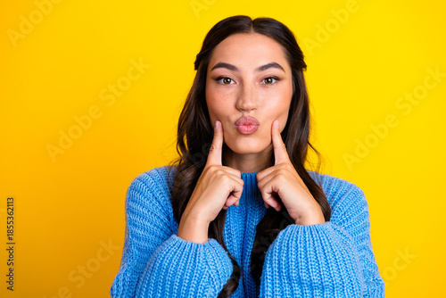 Schilderij op canvas Young mixed race woman in blue sweater making kissy face against bright yellow b