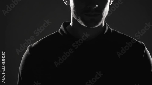 silhoutte of man in black suit under dramatic sharp white lighting