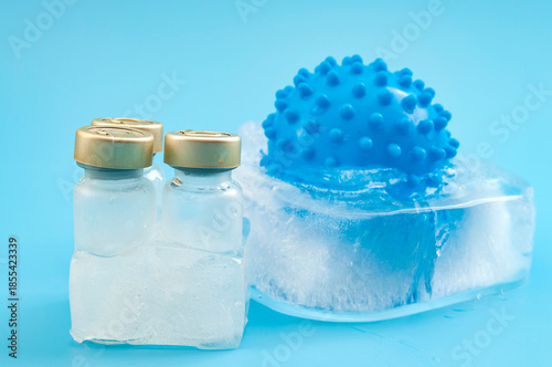 Frozen Vaccine Storage Concept with Medical Vials and Virus Model in Ice on Blue Background