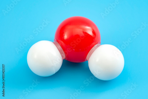 Chemistry backgrounds, chemical bonds and molecular structure of water concept with H2O plastic model molecule (oxygen in red and hydrogen in white) isolated on blue background