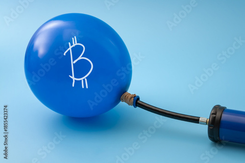 Inflating Bitcoin Bubble Concept with Hand Pump and Cryptocurrency Balloon on Blue Background