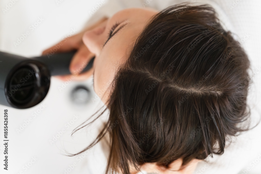 Fototapeta premium ドライヤーで髪を乾かしている女性 ビューティイメージ
