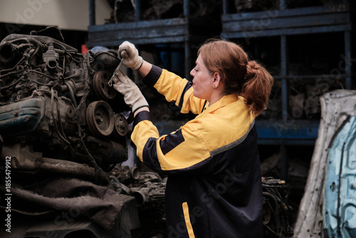 Foto Professional Hispanic mature female mechanic fixing used machines and auto engine spare parts in warehouse stacks, checking distribution stock in manufacturing factory, and industrial worker career