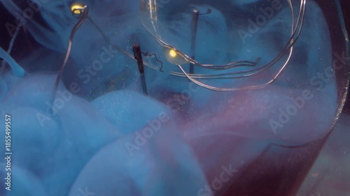 Vapor mix defocused. Broken light bulb. Color cloud spill on glowing garland. Blue fume paint swirl on red glitter abstract dark background.