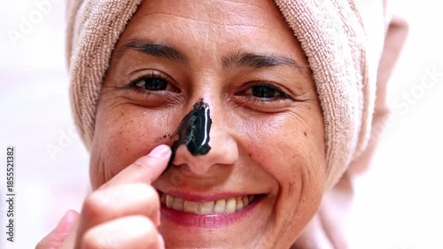 Mature woman applying a purifying black nose mask