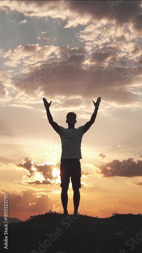 Silhouette of a person raising hands at sunset, embodying achievement, freedom, and connection with nature, vertical shot