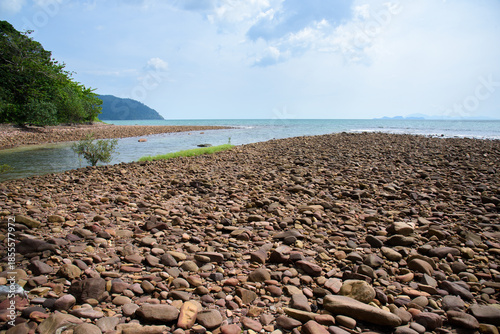 Rocks/stones on the  beach during a daylight on the islands, Thailand.Background image of the beach with sea in the distance with pebble stones.