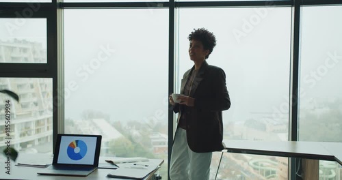 Confident analyst examining colorful graphs in modern workspace