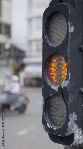 A vertical static view captures a traffic light transitioning between signals, reflecting stability, governance, and the structured rhythm of modern city life. Urban order.