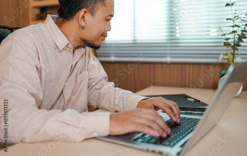 Serious and focused Asian man, businessman, freelancer, student working studying at home using laptop, Sitting at table and talking on video call, typing. 