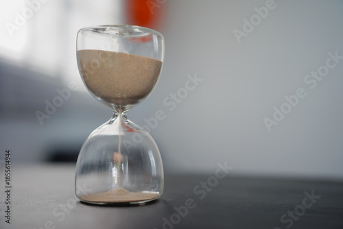 Antique hourglass sand timer on the beach symbolizing the passing flow of time, countdown, and future business deadline concept