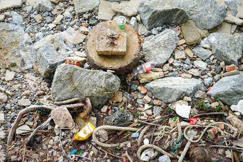 Plastic bottles and garbage polluting a pebble beach 
