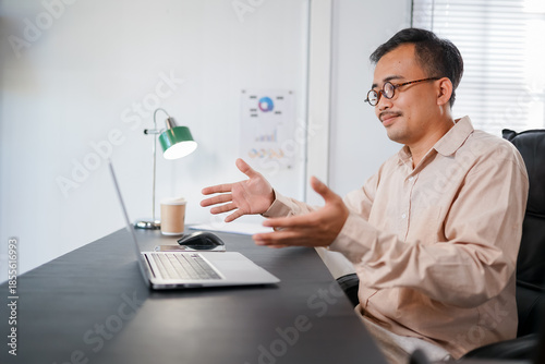 Portrait of a cheerful Asia man having video call on laptop computer.
