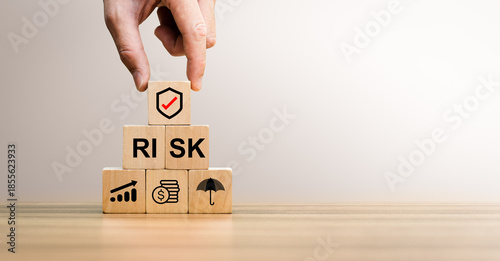 Foto Risk management concept with hand placing shield icon block on stacked wooden cu