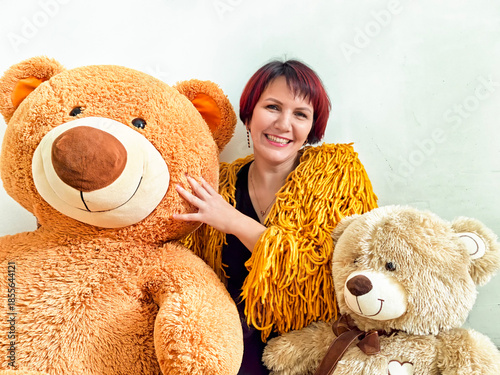 Woman smiles with large teddy bears in a cheerful indoor space during bright daylight