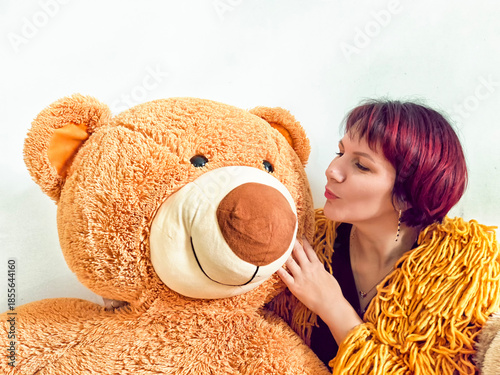 Woman interacts with a large teddy bear in a cozy indoor setting, showcasing a playful and light-hearted moment
