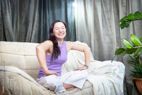 Woman enjoys time at home in a cozy space surrounded by plants and soft light focused on self care and relaxation moments