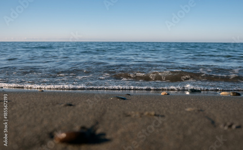 Calm sea waves touching sandy beach on a clear summer day