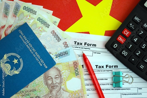 Vietnamese dong money bills and calculator with tax form on flag close up. Taxation and accounting concept