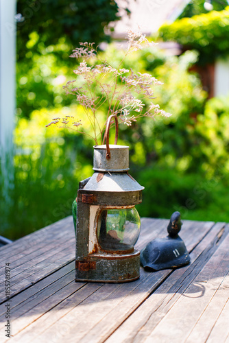 Lantern with flowers on wooden table in garden setting