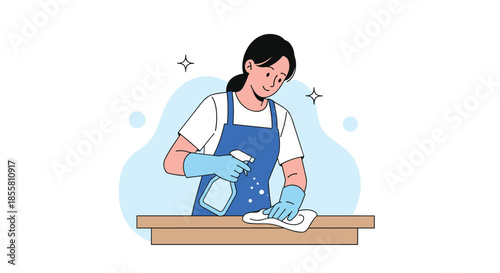 Diligent young woman wearing an apron and gloves uses a spray bottle and cloth to clean and disinfect a wooden table surface.