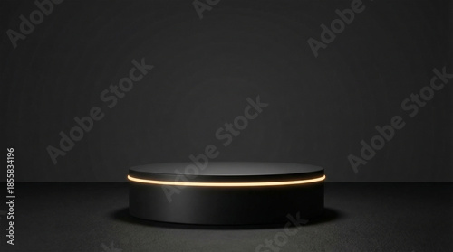 A sleek black cylindrical podium with a subtle glowing gold ring stands prominently on a dark, minimalist stage against a muted wall.