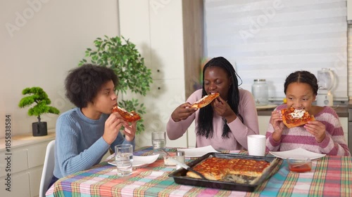 African american mother and daughters enjoying homemade pizza