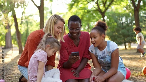Diverse group of female friends using a smartphone in the park