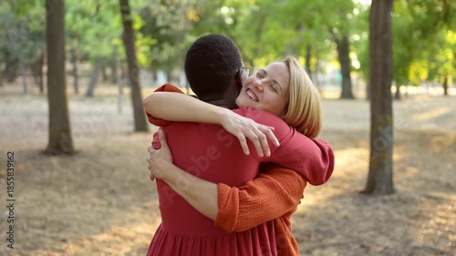 Two happy multiethnic women hugging each other in a park