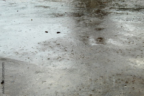 raindrops falling on a wet concrete surface during cloudy weather