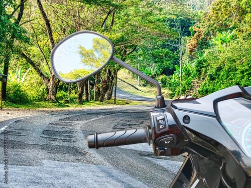 Left motorcycle handlebars, mirror, headlight switch, horn switch, and motorcycle signs light switch on the avenue tree road,