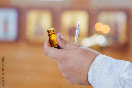 Holding a small bottle and a silver object in a church
