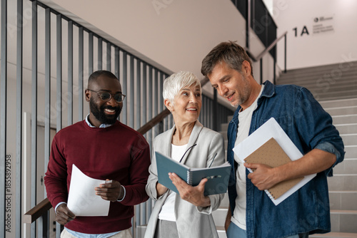 Canvastavla Three Professionals Discuss Documents In A Modern Office Hallway During Friendly
