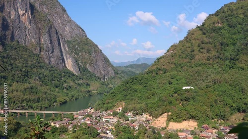 ScenicValley landscape in Nong Khiew, Ngoi Distict, Luang Prabang features a lush green forest and river view framed by stone cliffs and mountain peaks under a clear sky