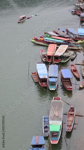 Small motor boats and fishing ships travel across the river  and transport dock port under a clear sky reflection