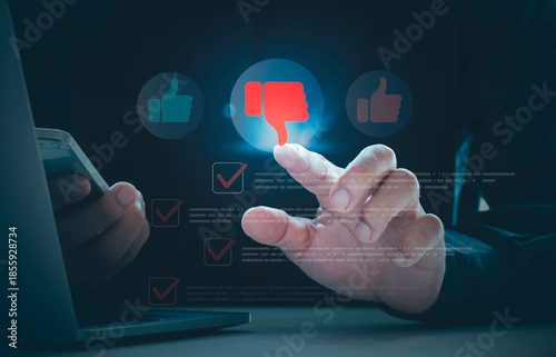 Fotografie User typing negative online review with thumbs down icon for bad customer feedback, service criticism, and dissatisfaction impacting digital reputation while using smartphone and laptop device