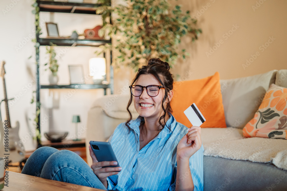 Fototapeta premium Woman smiling buying online with credit card on smartphone