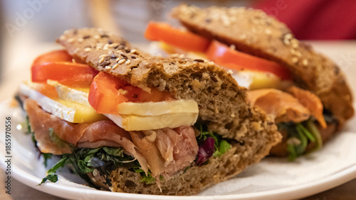 Foto appetizing whole grain bread sandwich with brie cheese, prosciutto ham and tomat