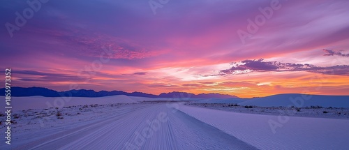 Colorful desert sunset over white sand dunes.