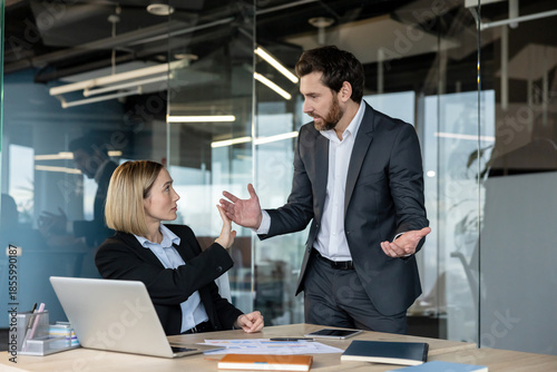 Картината върху платно Male and female colleagues in a tense office confrontation, woman gestures stop