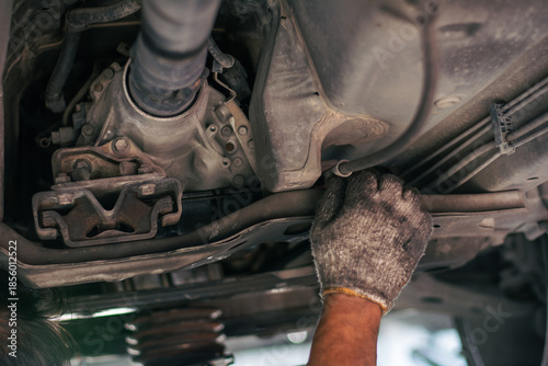 Foto A professional technician checking the transmission housing, rubber mounts, and driveshaft under a vehicle during a routine maintenance inspection