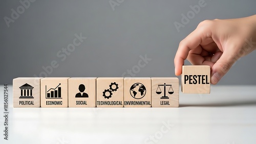 Business strategy concept with pestel analysis blocks on a table with a hand placing the final piece