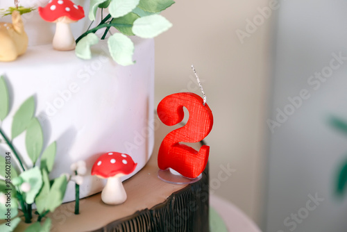 Red textured number two birthday candle on decorated cake
