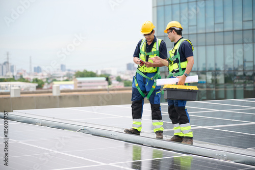 Engineers or workers is inspecting the solar panels on the rooftop with a city view