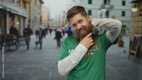 Bilde på lerret Smiling volunteer man in green shirt uses hand to pull beard on busy sunlit street; compassion service