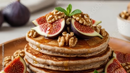Delicious pancake stack topped with fresh figs, walnuts, and mint on wooden plate