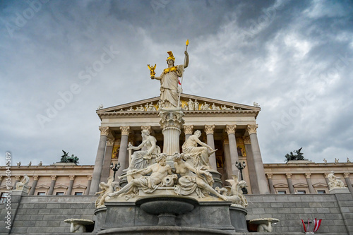 Vienna, Austria: Parliament Building. Pallas Athena Fountain located in front of the Austrian Parliament with dramatic grey clouds in background.  
