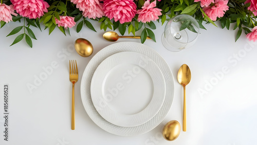 Elegant table setting with gold cutlery and pink flowers on white tablecloth for formal dinner or special occasion