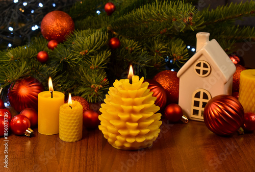 Christmas beeswax pine cone candle and fir tree branch on wooden table close-up stock photo images. Yellow burning beeswax candles and Christmas decorations still life stock photo