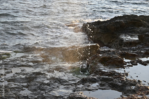 Sea geyser erupting from rocks under wave pressure

